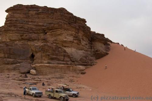 Tourists climb the sand hill.